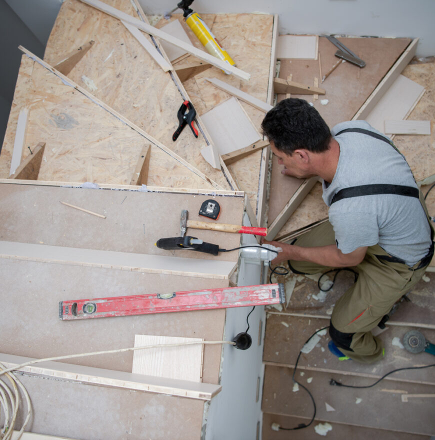 work in progress on stylish interior professional carpenter installing wooden stairs in big modern two level luxury apartment